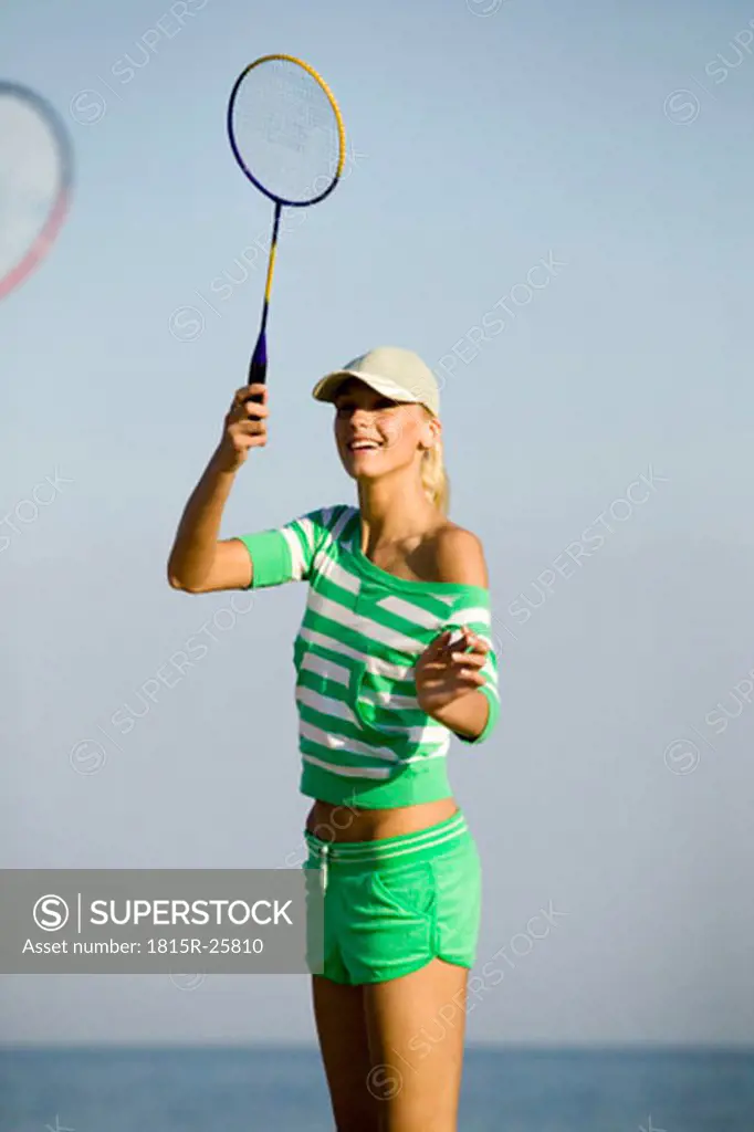 Young woman playing badminton on beach