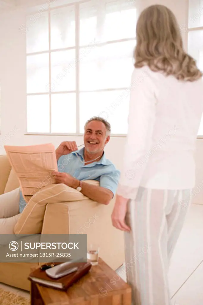 Mature couple in living room, man looking at woman, smiling
