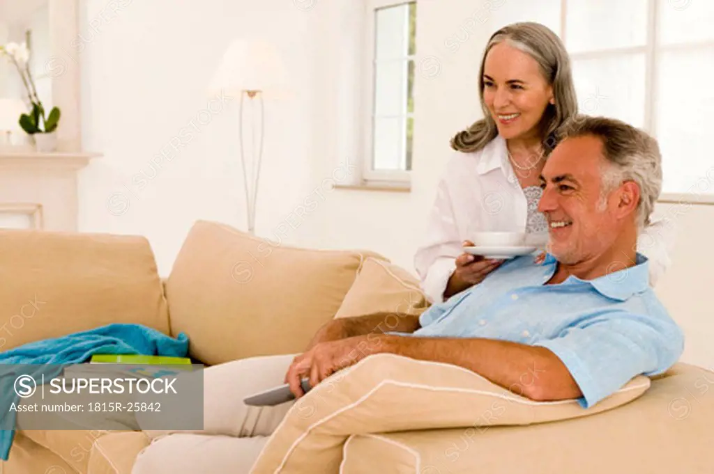 Mature couple sitting on sofa, watching TV, side view