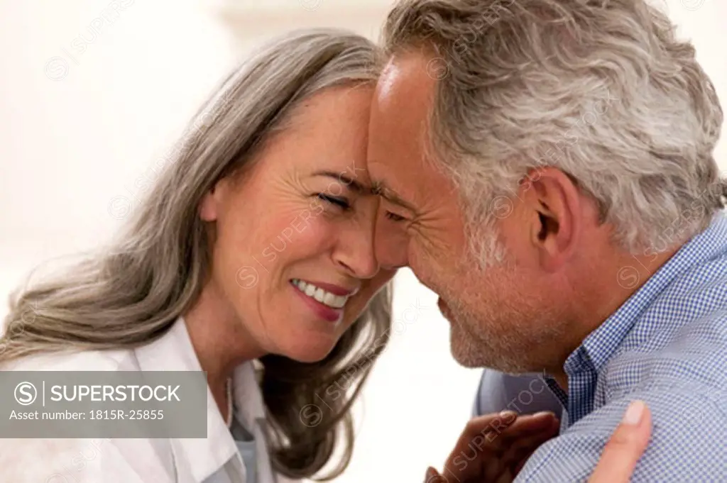 Mature couple embracing, smiling, close-up