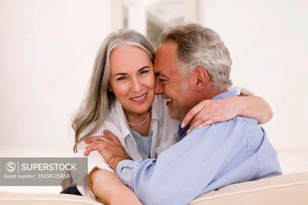 Mature couple embracing on sofa, smiling