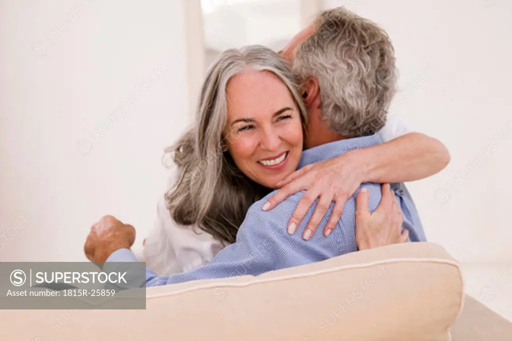 Mature couple embracing on sofa, smiling