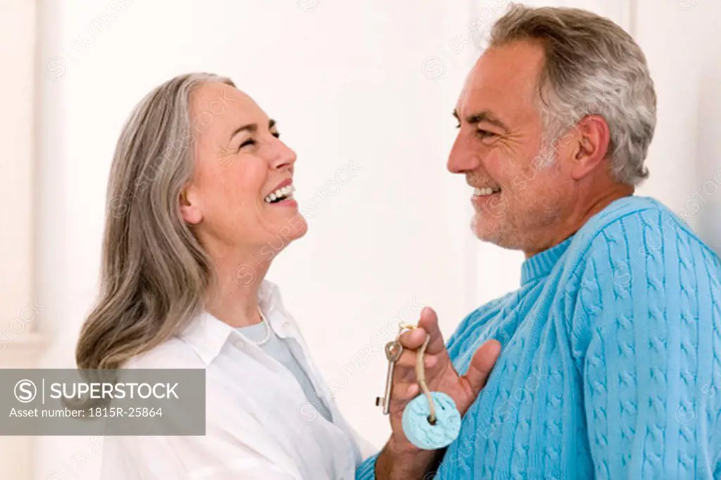 Mature couple smiling, man holding key, close-up