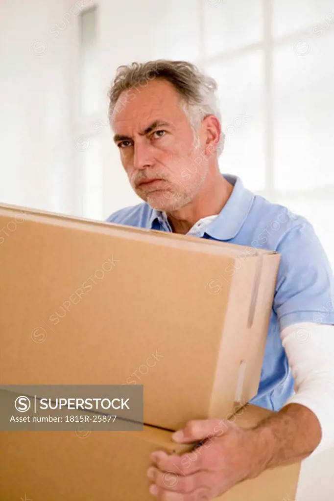 Mature man holding carton, looking away, close-up