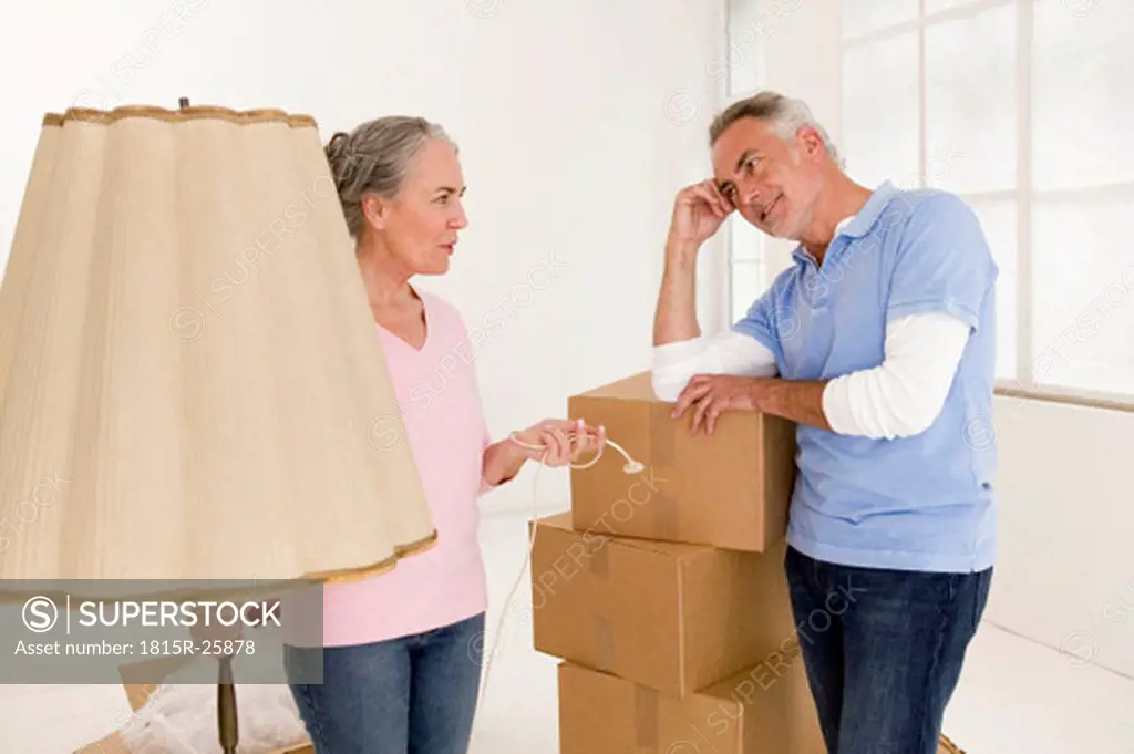 Mature couple in living room with cardboard boxes, discussing