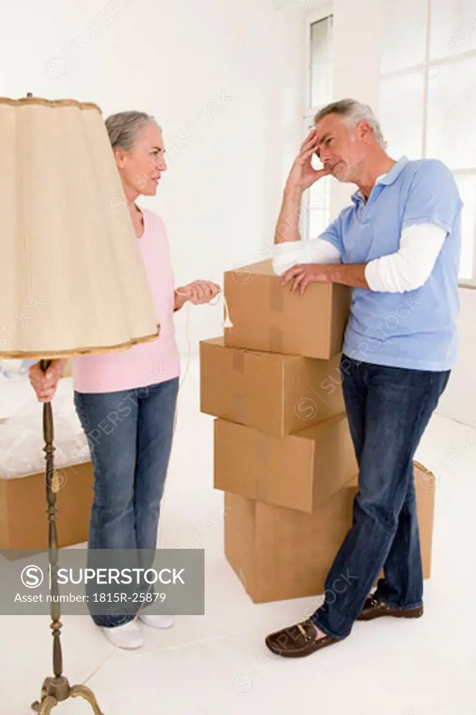 Mature couple in living room with cardboard boxes, discussing