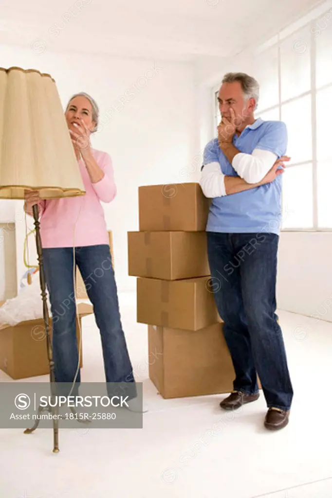 Mature couple in living room with cardboard boxes, thinking