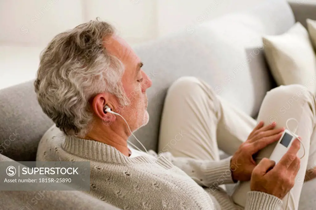 Mature man listening to MP3 player, close-up, elevated view