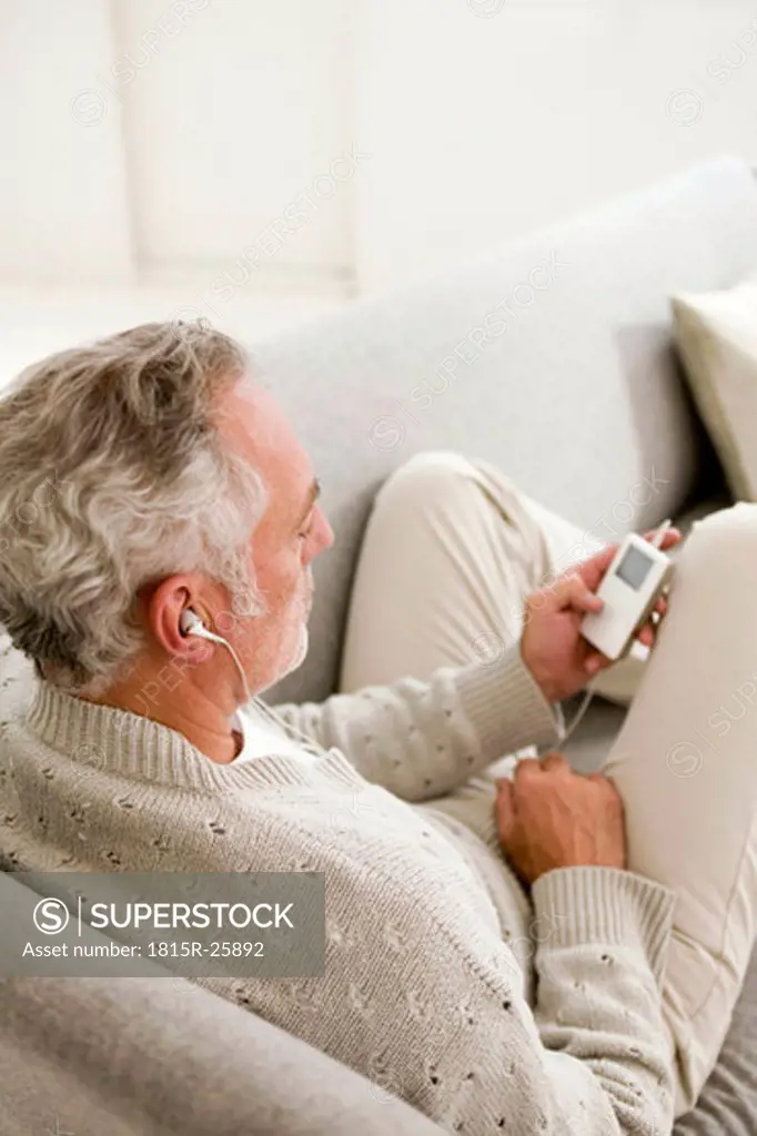 Mature man listening to MP3 player, close-up, elevated view