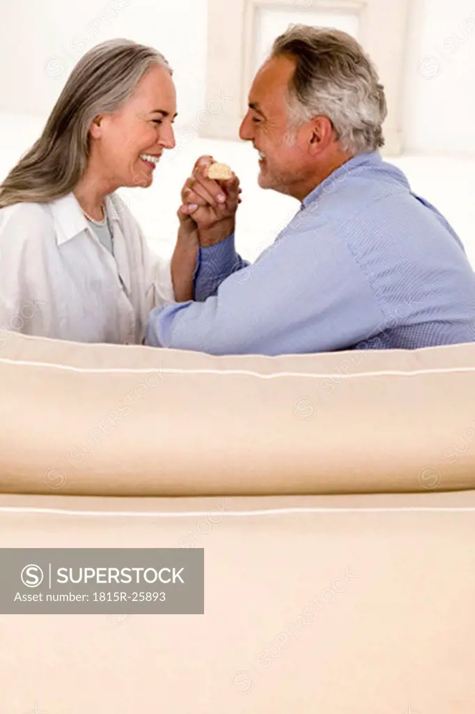 Mature couple sitting on sofa, smiling, side view
