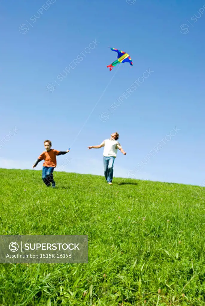 Father and son (4-7) flying kite, low angle view