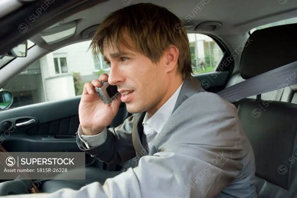 Businessman using mobile phone in car, side view, close-up