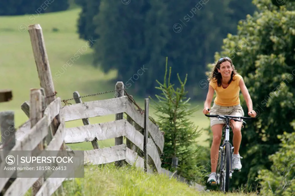 Young woman riding bicycle in mountains, smiling