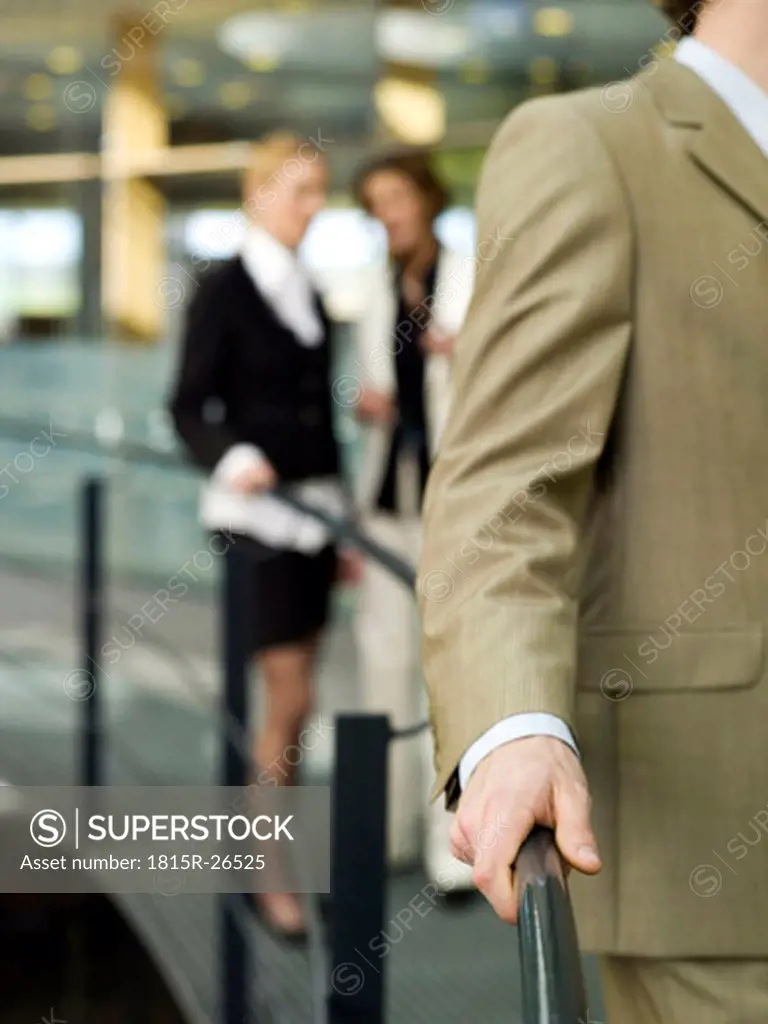 Women talking behind back of young businessman