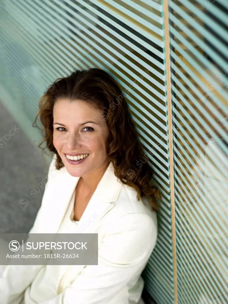Businesswoman sitting on floor, smiling, elevated view, portrait