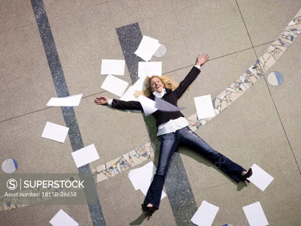 Woman lying on floo surrounded by papers
