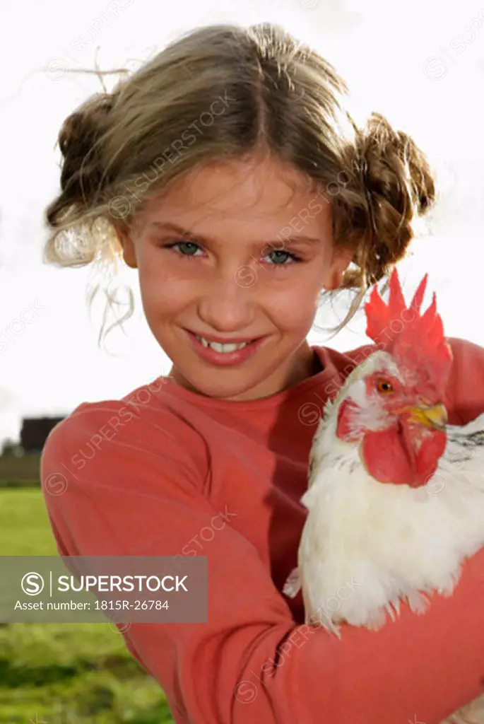 Girl (7-9) holding cock, portrait, close-up