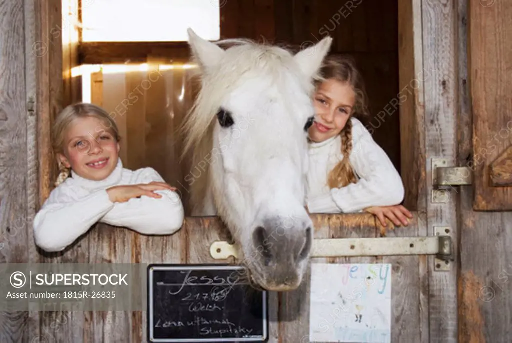 Two girls with horse in stable, portrait