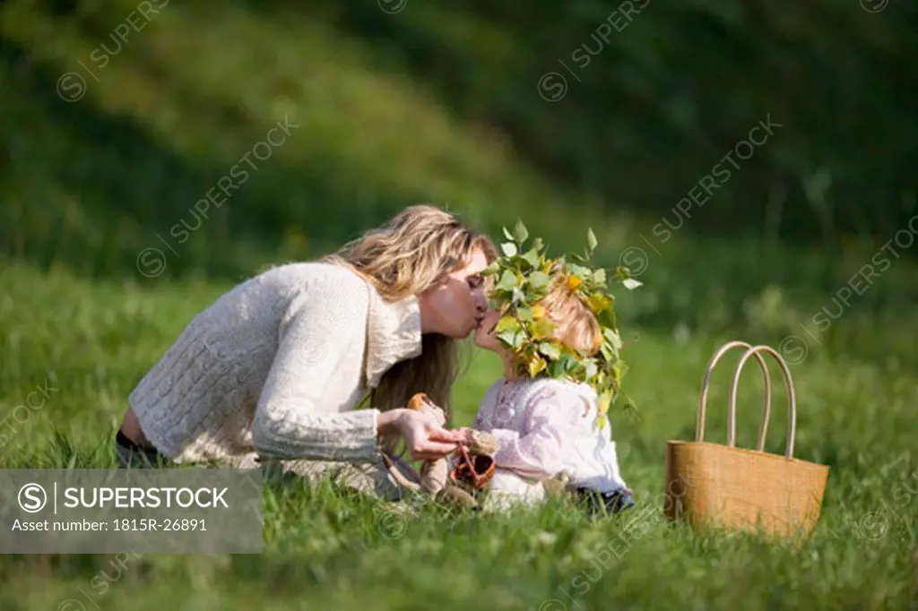 Mother and daughter in meadow, doughter wearing wreath on head
