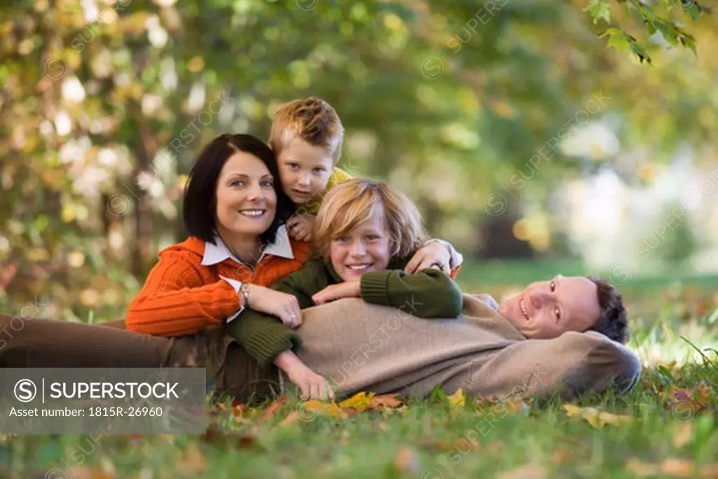Parents with two sons lying in meadow