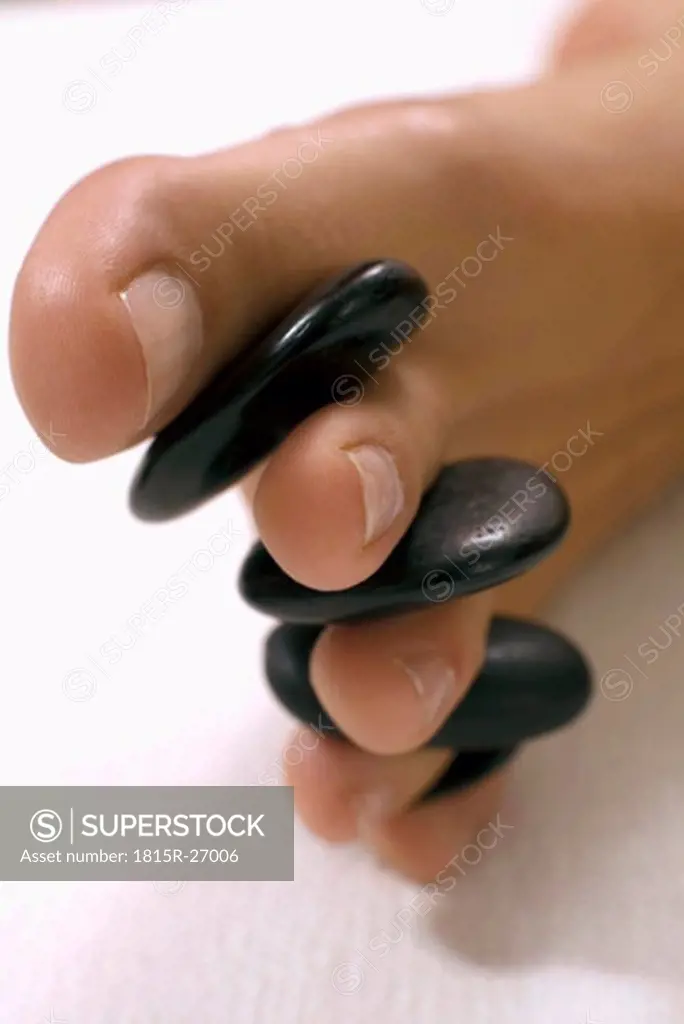 Woman receiving hot stone massage on feet, close-up