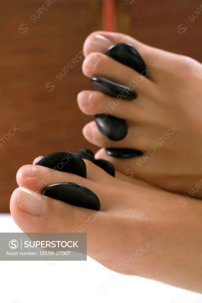 Woman receiving hot stone massage on feet, close-up