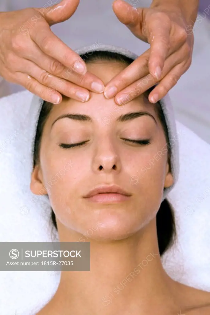 Young woman receiving forehead massage, eyes closed, elevated view