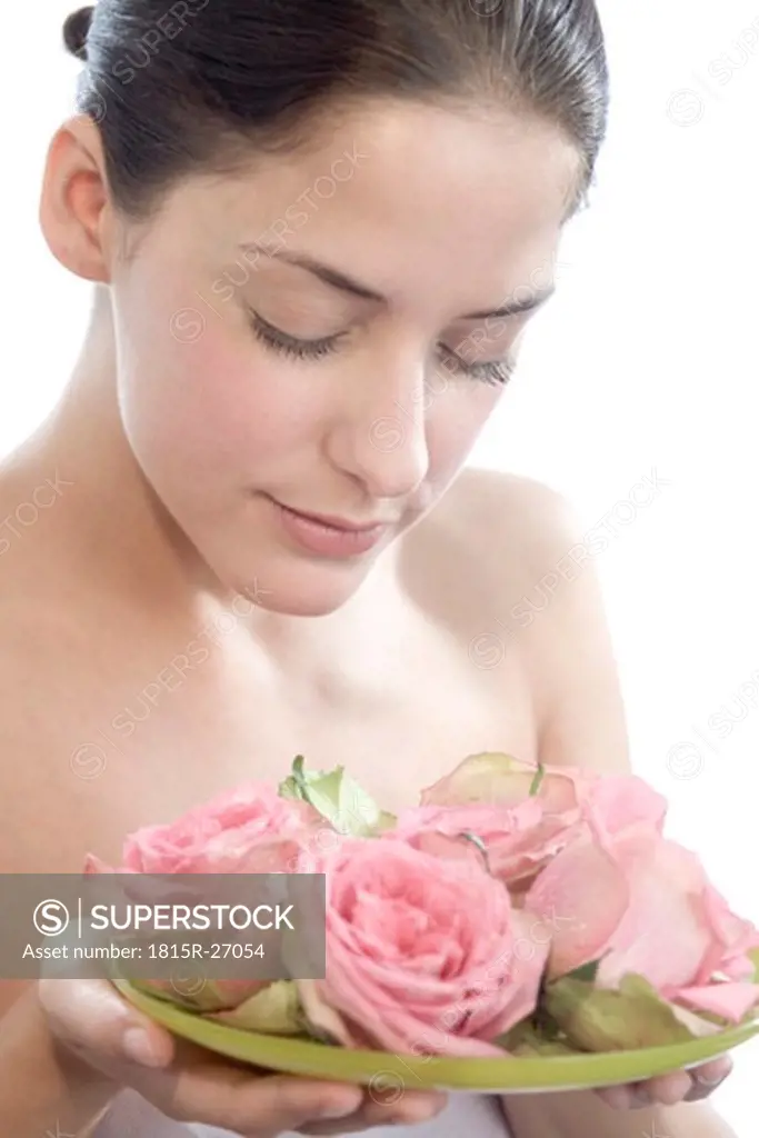 Young woman smelling rose flowers, eyes closed, close-up