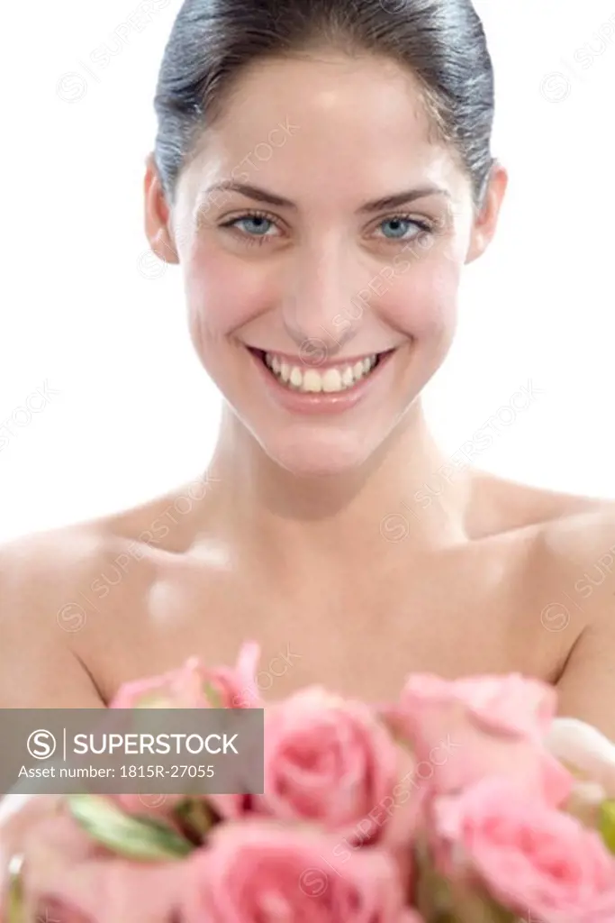 Young woman holding rose flowers, smiling, portrait