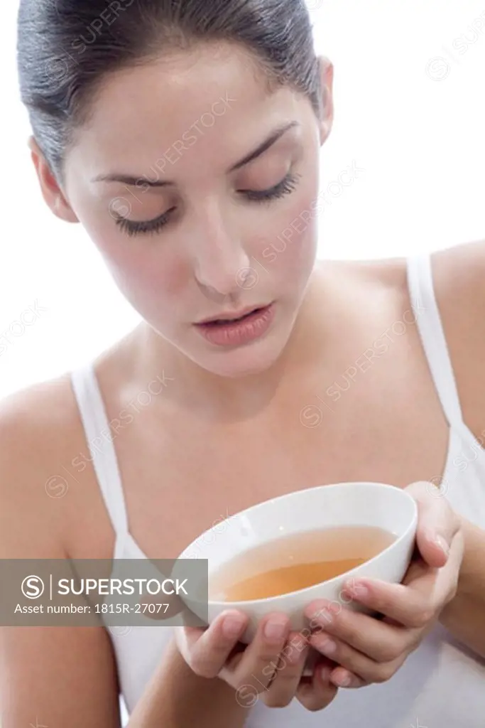 Young woman holding tea bowl, close-up