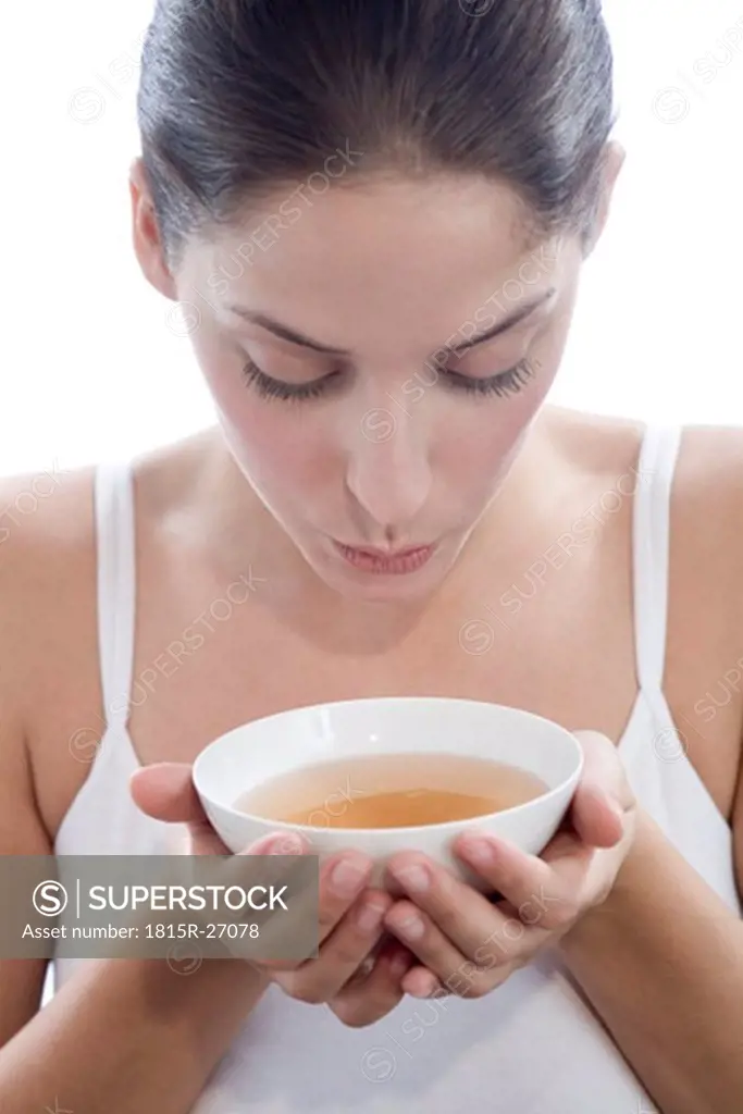 Young woman holding tea bowl, close-up