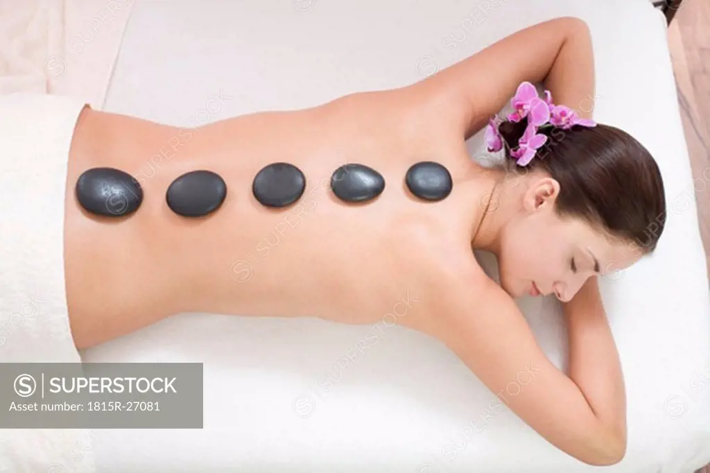 Young woman receiving hot stone massage, elevated view