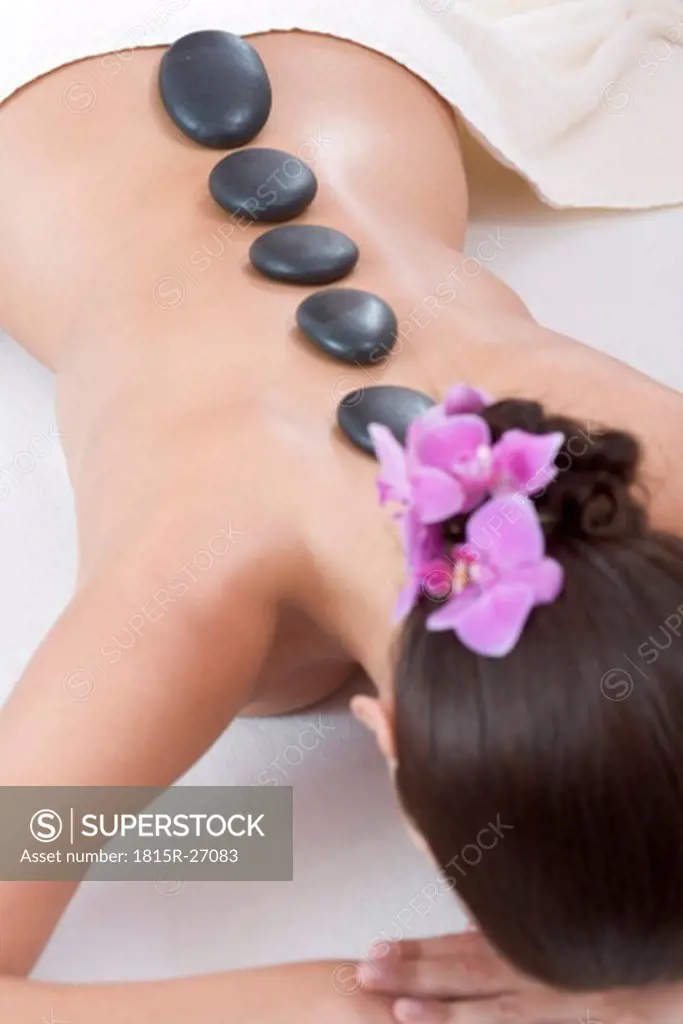 Young woman receiving hot stone massage, rear view