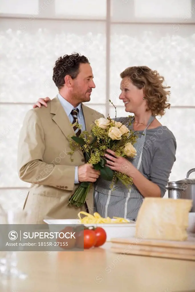 Mature couple in kitchen with flower bouquet