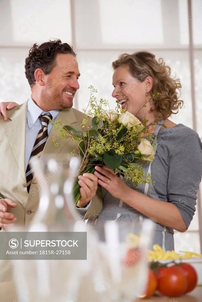 Mature couple in kitchen with flower bouquet