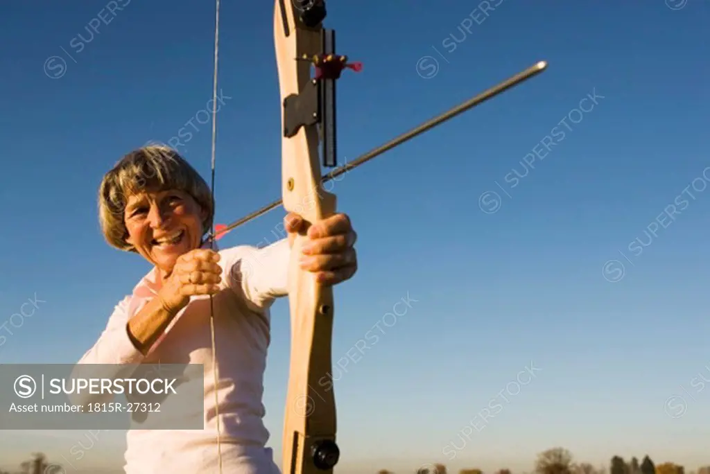 Senior adult woman using bow and arrow