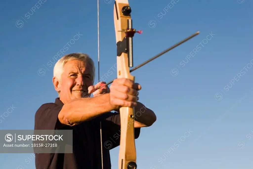 Senior adult man using bow and arrow
