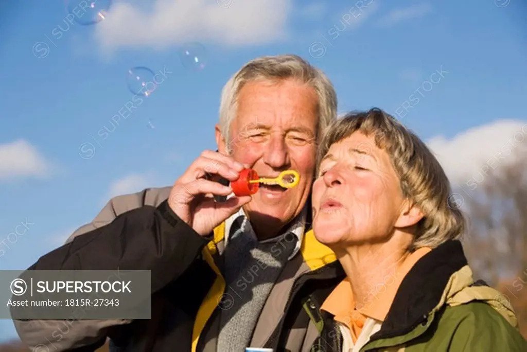 Senior couple blowing bubble wand, close-up