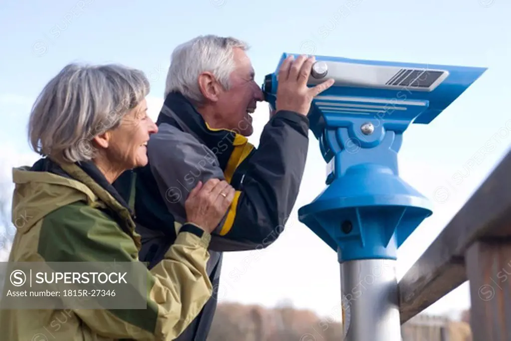 Senior couple, man looking through telescope, side view