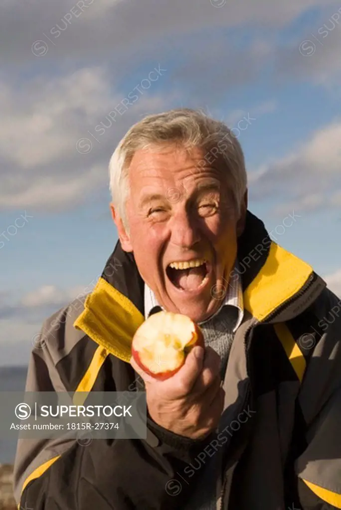 Senior adult man eating apple