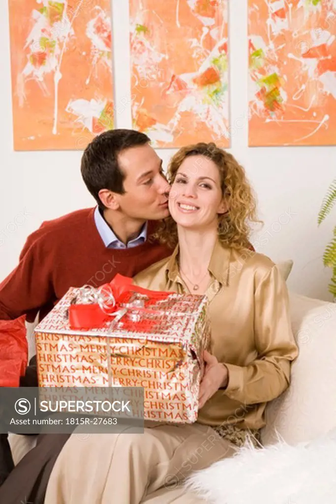 Couple sitting on sofa, man kissing woman