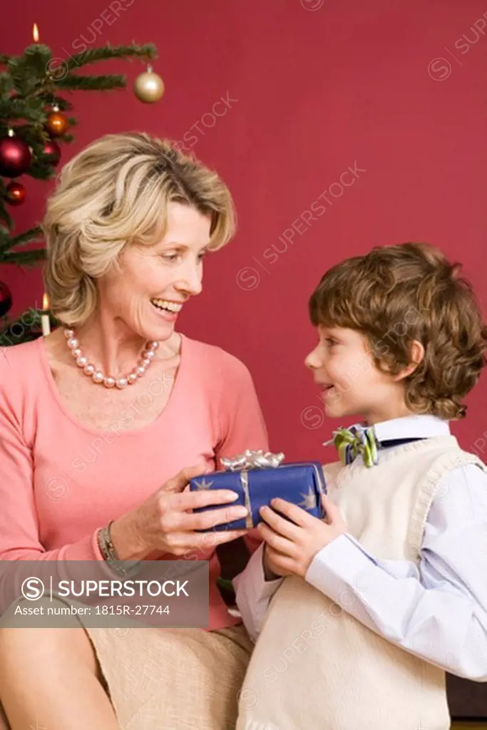 Little boy giving Christmas present to grandmother