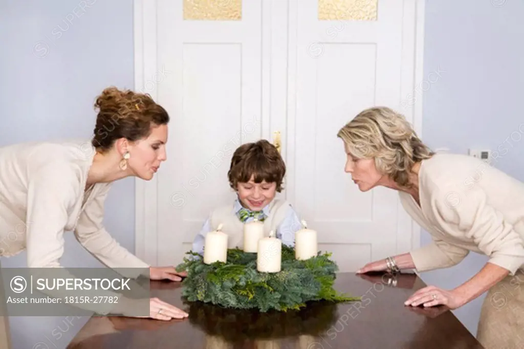 Mother, Grandmother and grandson blowing out Advent wrath