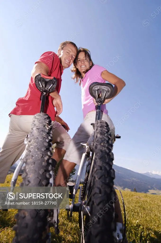 Young couple on bicycle, smiling, low angle view, portrait