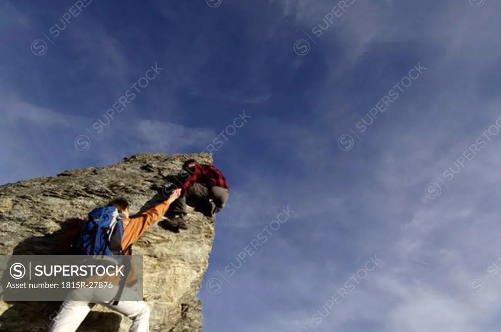 Couple climbing on summit, rear view