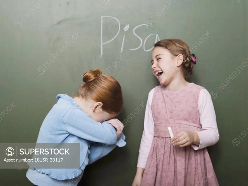 Girls standing in front of blackboard, laughing
