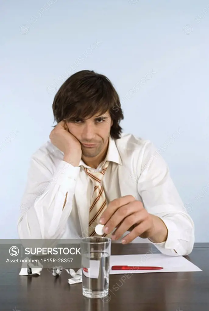 Man holding pill, sitting on desk