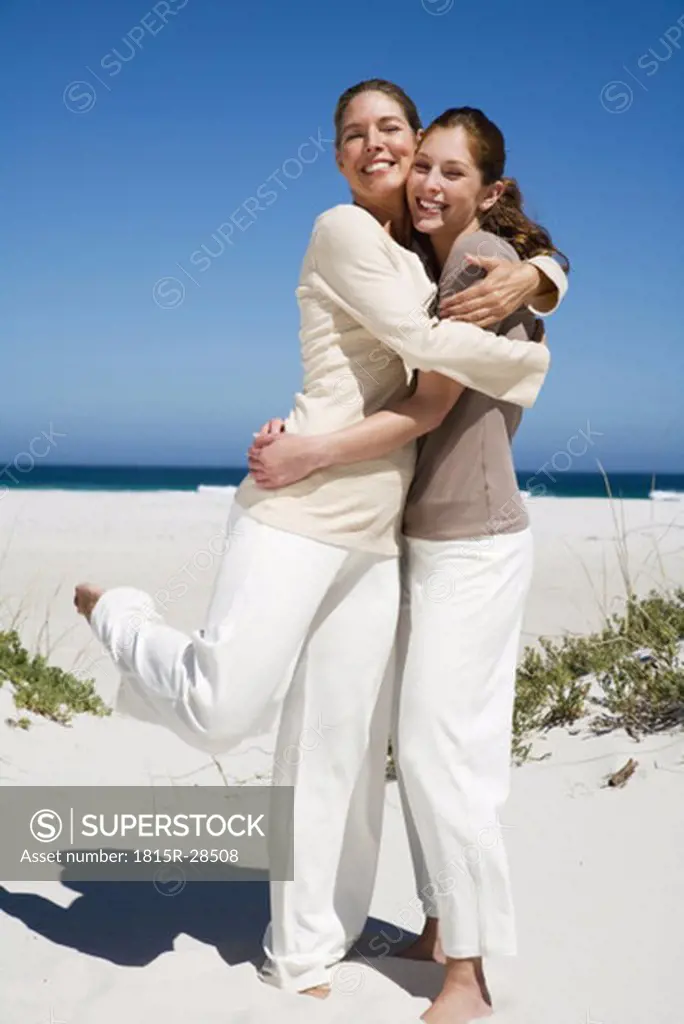 Mother and daughter embracing on beach