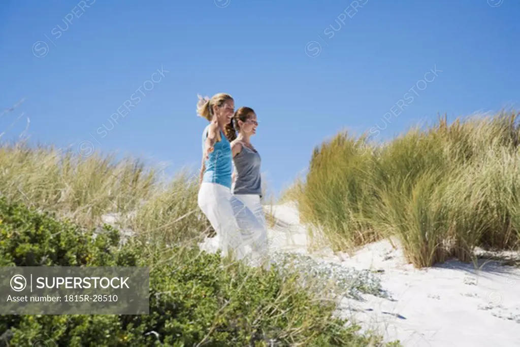 Mother and daughter running on beach, hand in hand