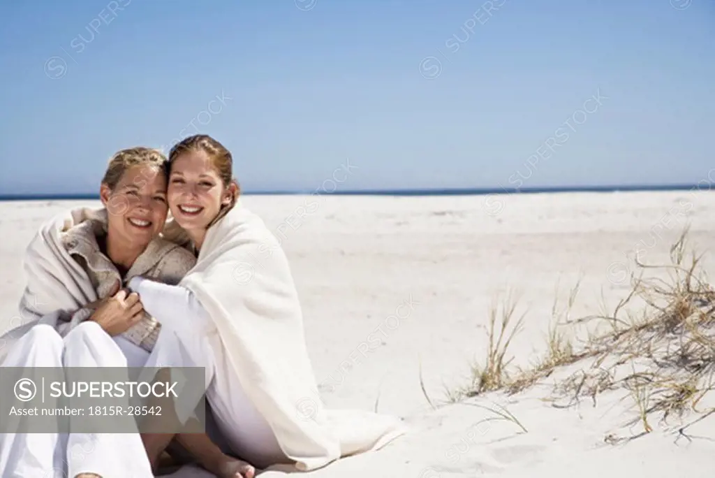 Mother and daughter sitting on beach